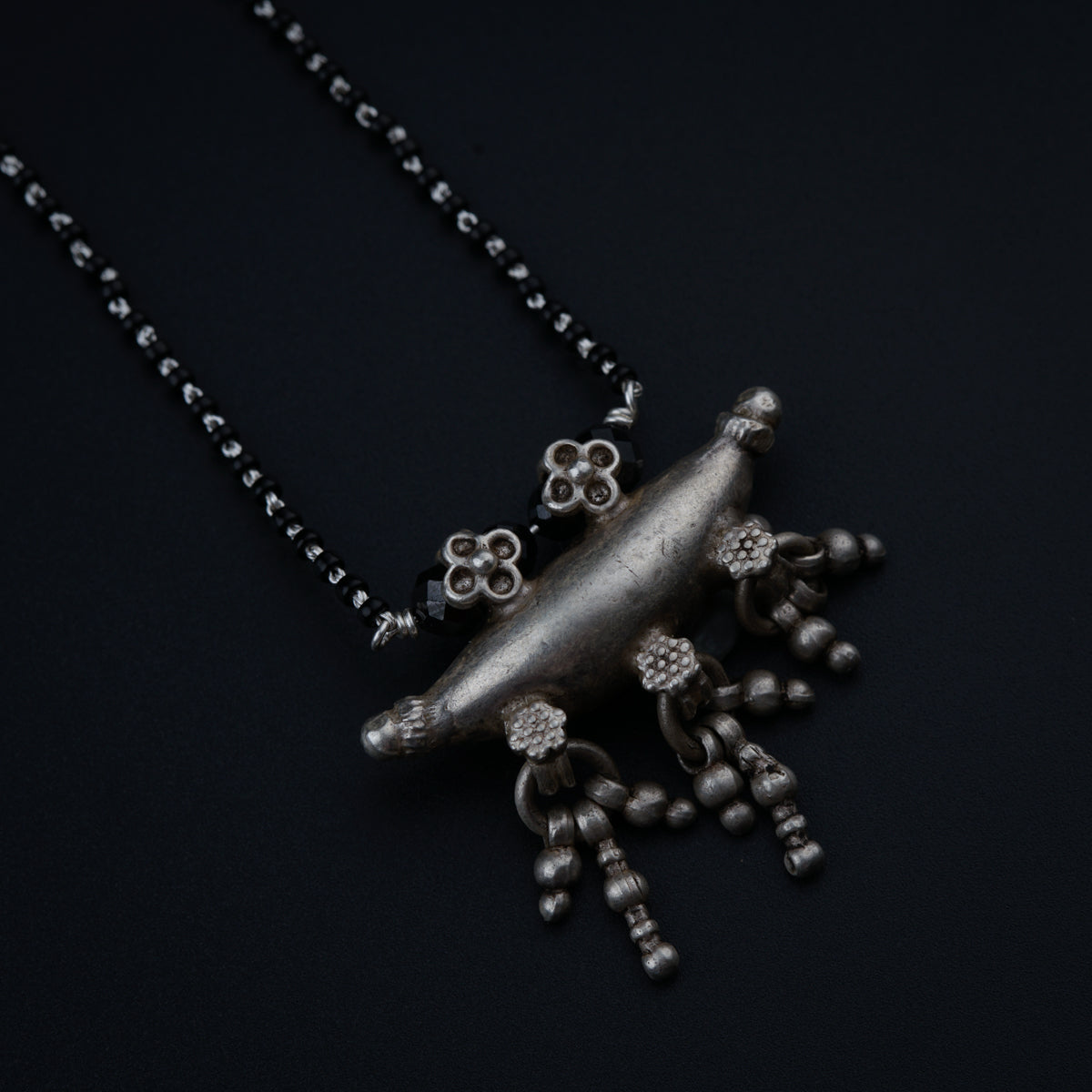 a necklace with a silver frog on a black background