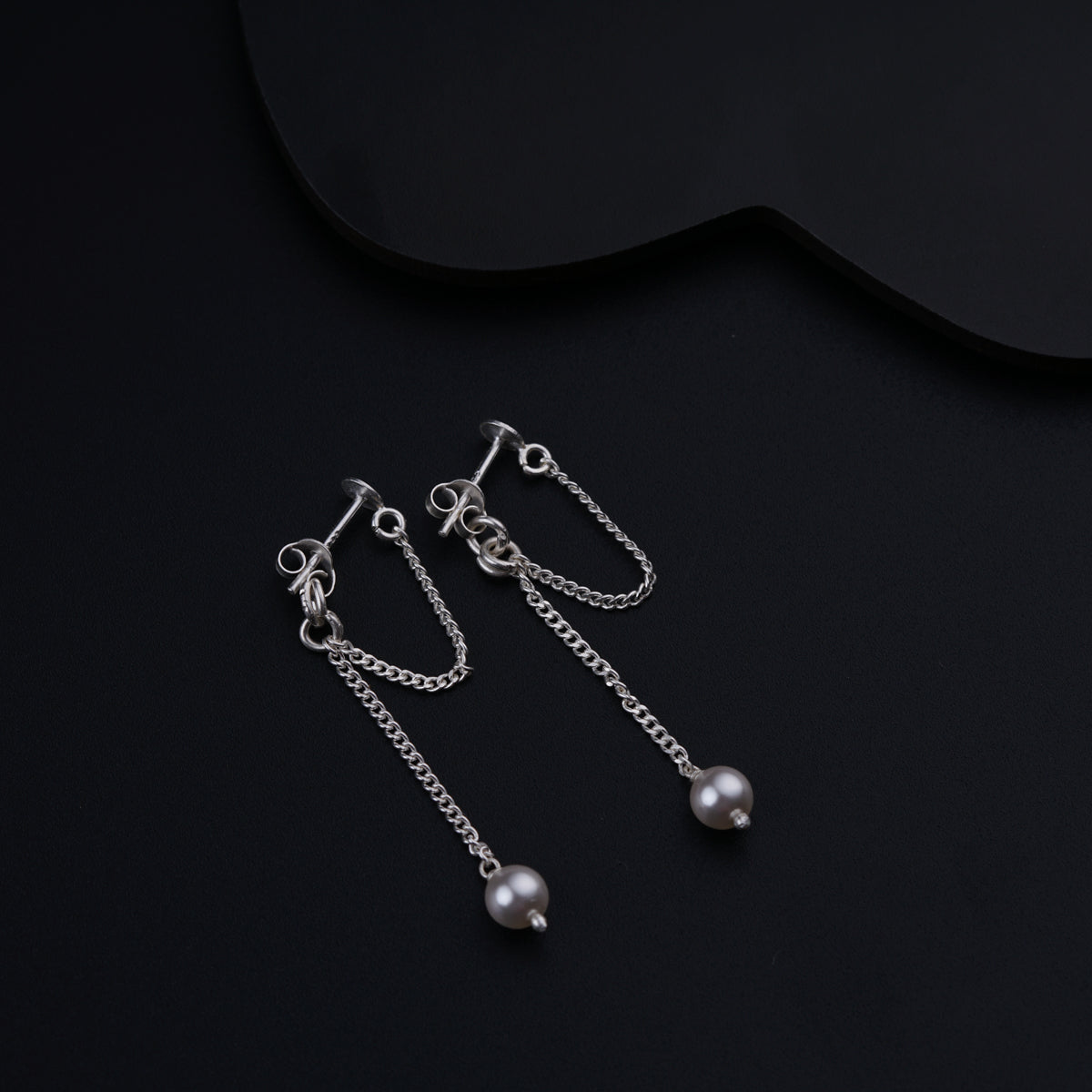 a pair of earrings with pearls hanging from them