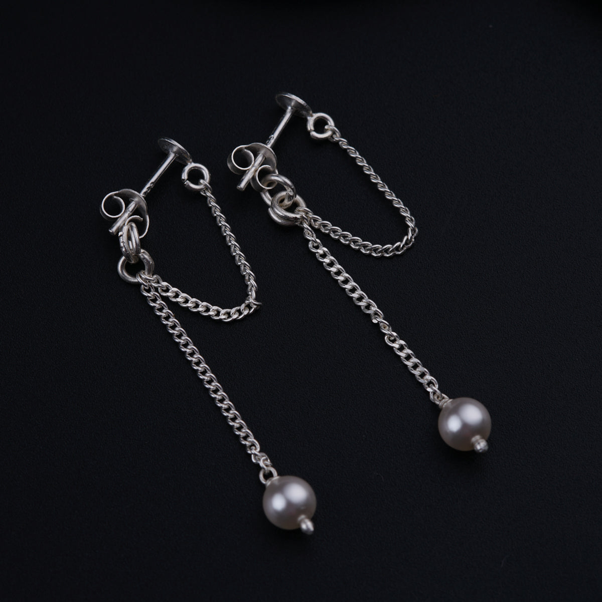 a pair of earrings with pearls hanging from them