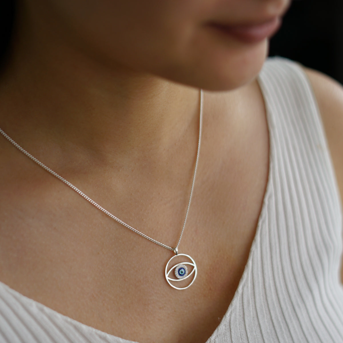 a woman wearing a necklace with an evil eye