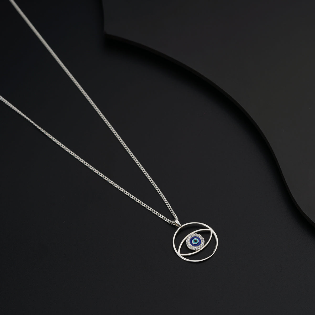 a silver necklace with an evil eye on it