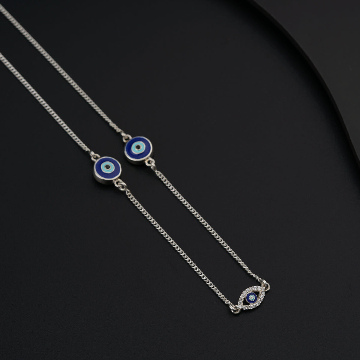 a pair of evil eye necklaces on a black surface