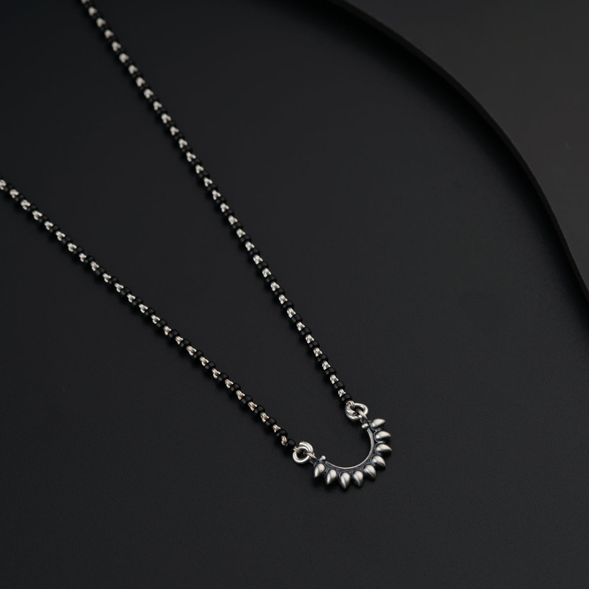 a necklace with a circular design on a black surface