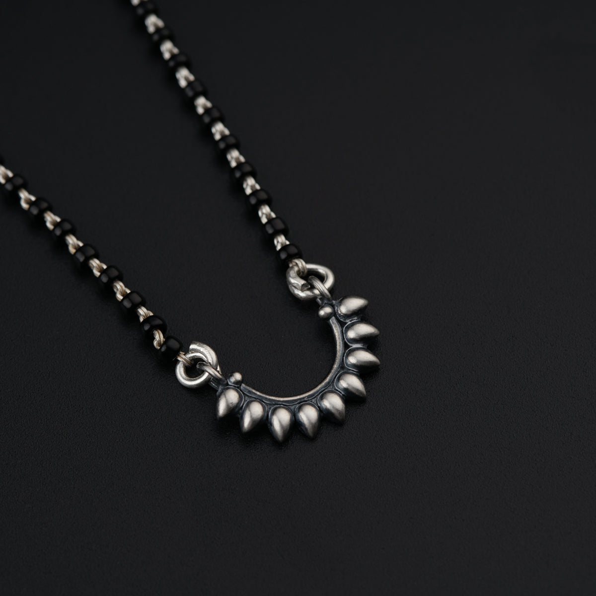 a silver necklace with spikes on a black background