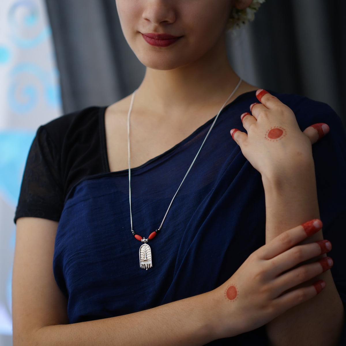 a woman wearing a necklace with a red bead