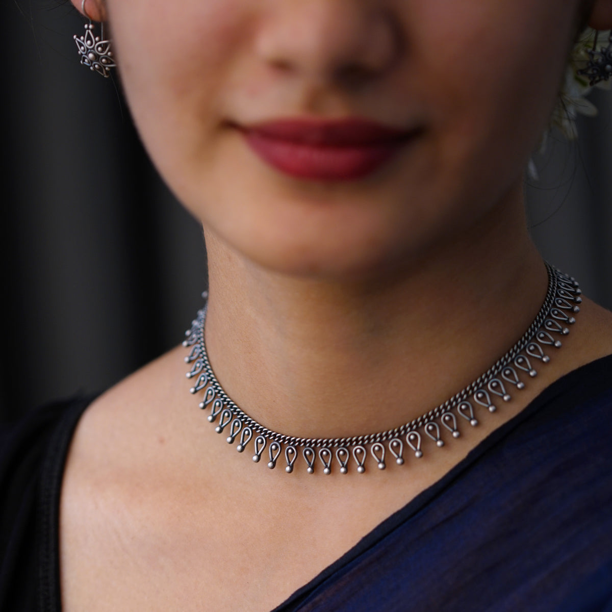a close up of a woman wearing a necklace and earrings