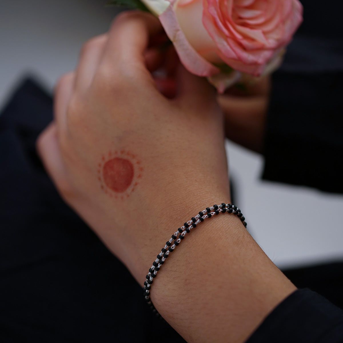 a person holding a flower and a bracelet