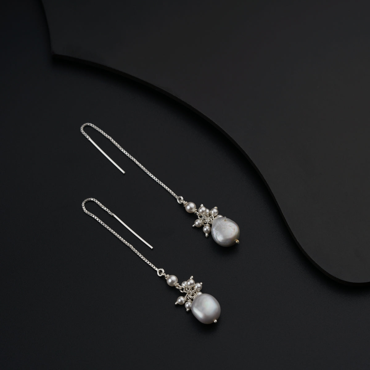a pair of pearl and crystal earrings on a black surface