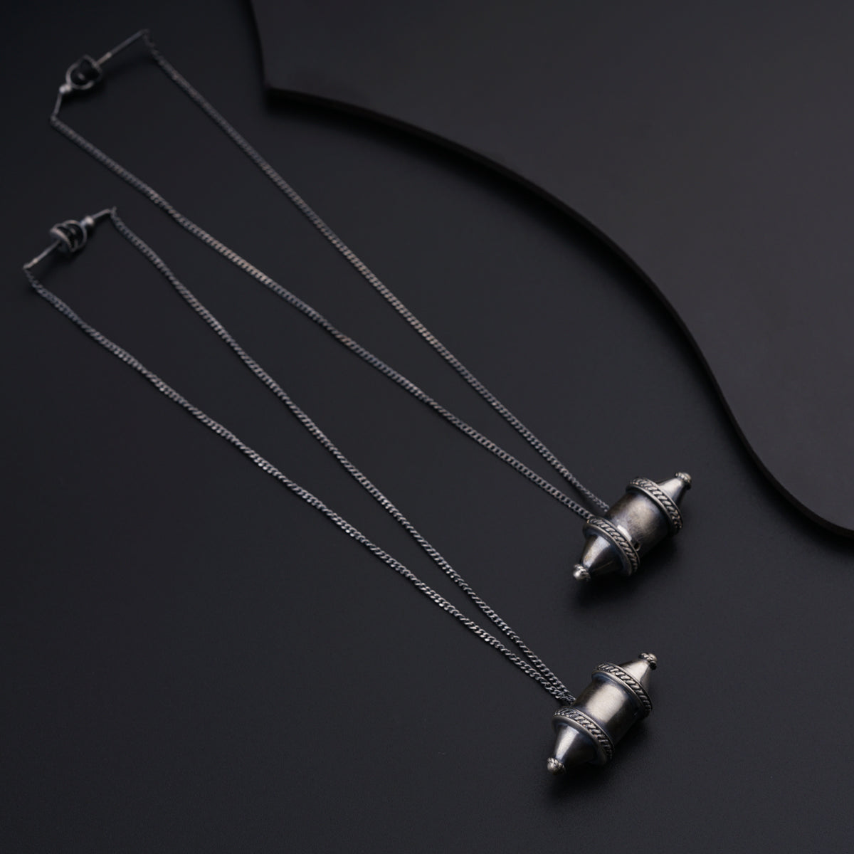 three silver necklaces on a black surface