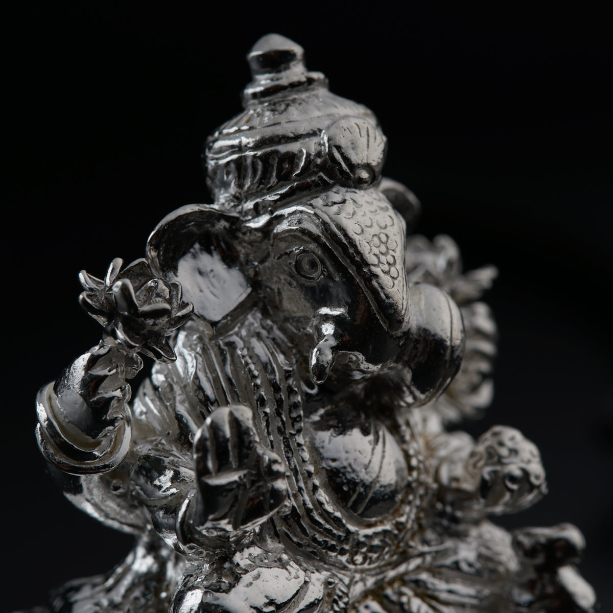 a close up of a silver statue on a black background