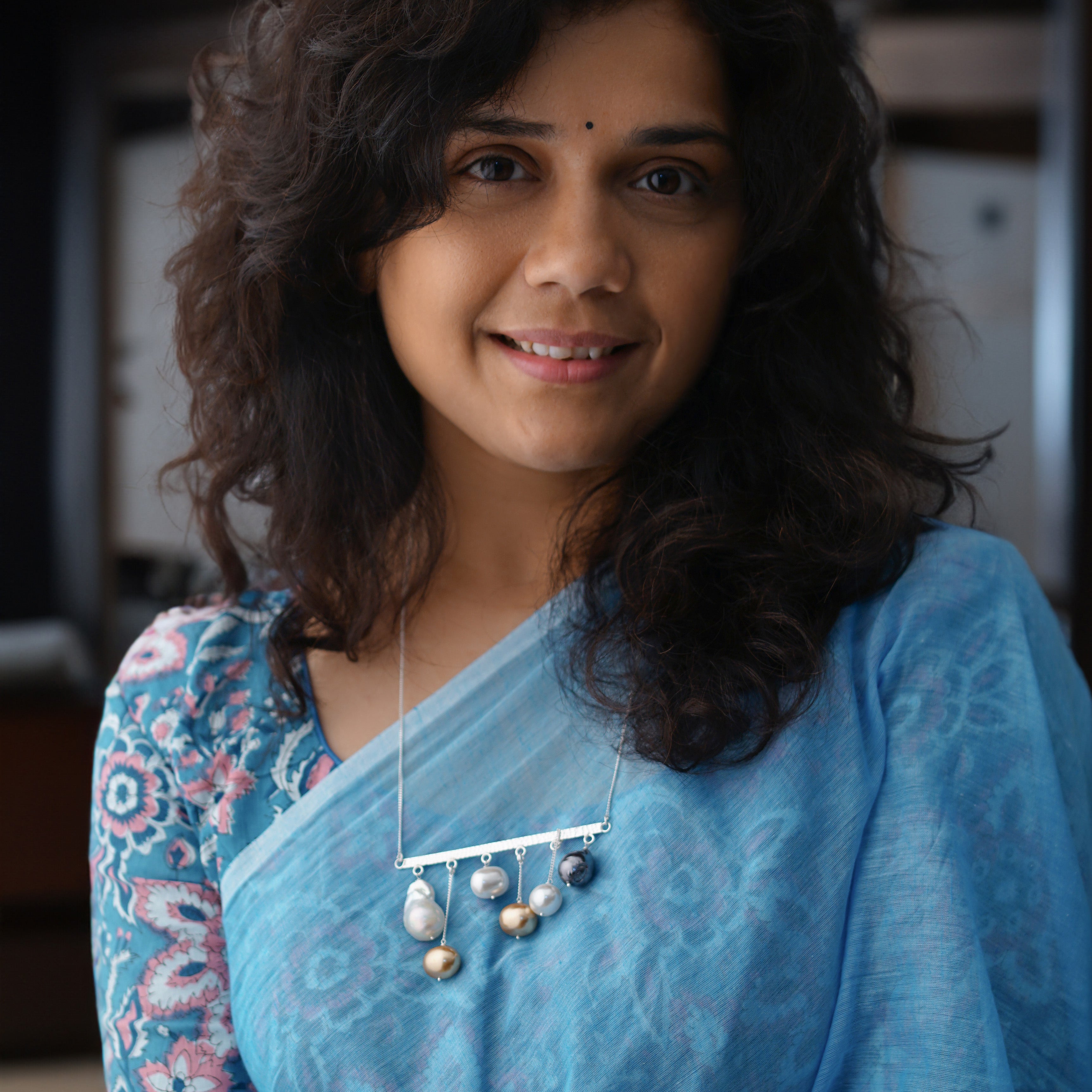 a woman wearing a blue sari and a necklace