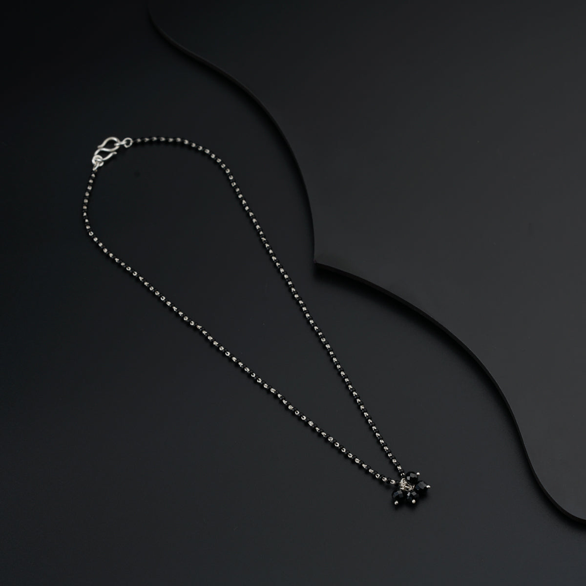 a black and white photo of a necklace on a black background