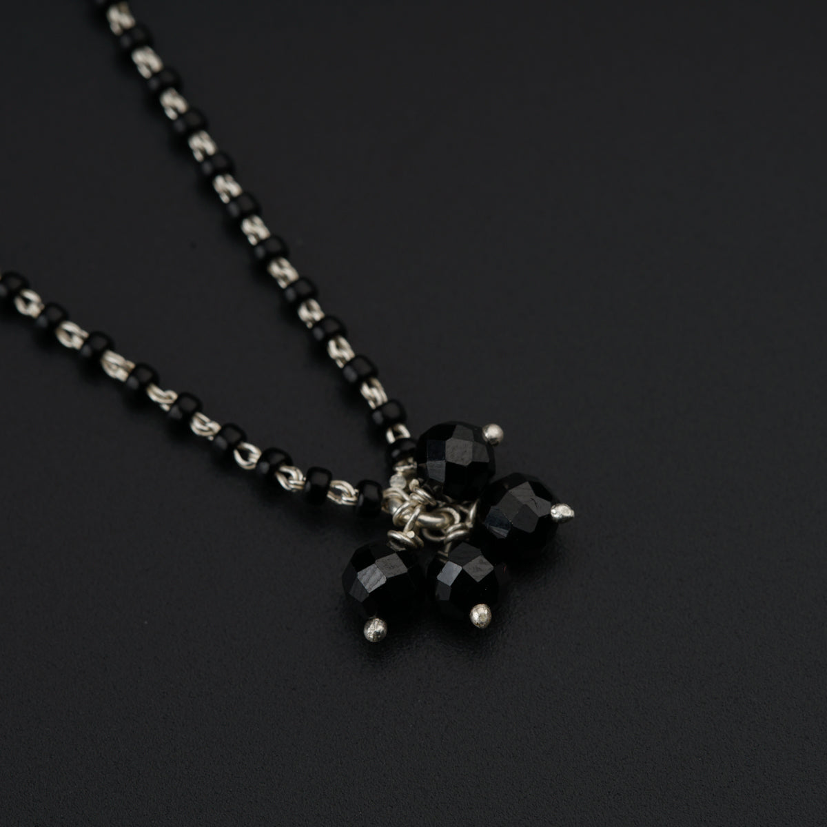 a black and silver necklace on a black surface