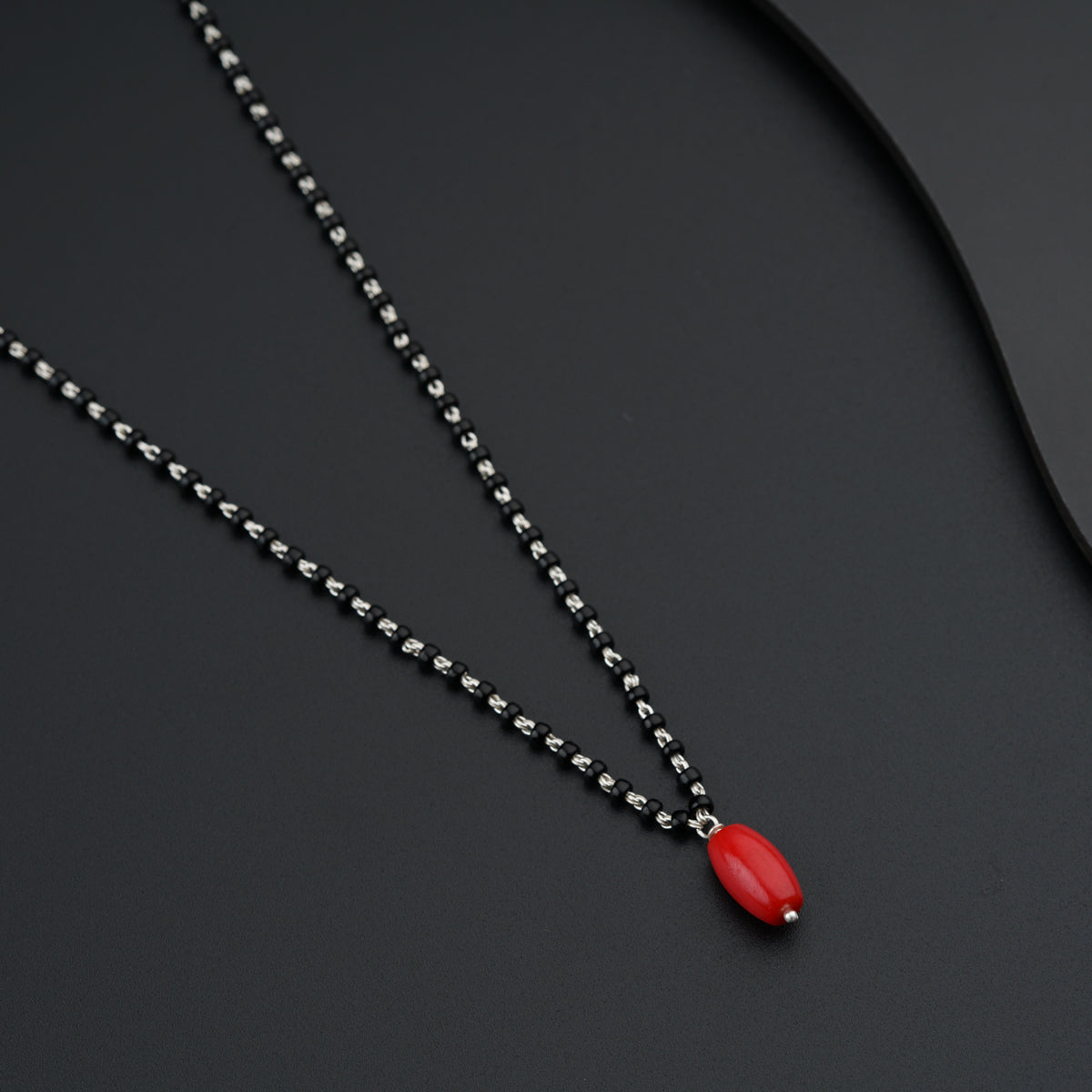 a necklace with a red pendant on a black surface