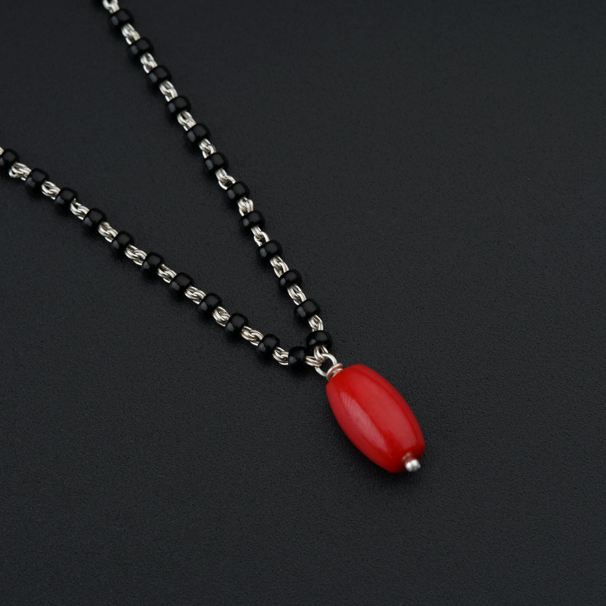 a necklace with a red pendant on a black background