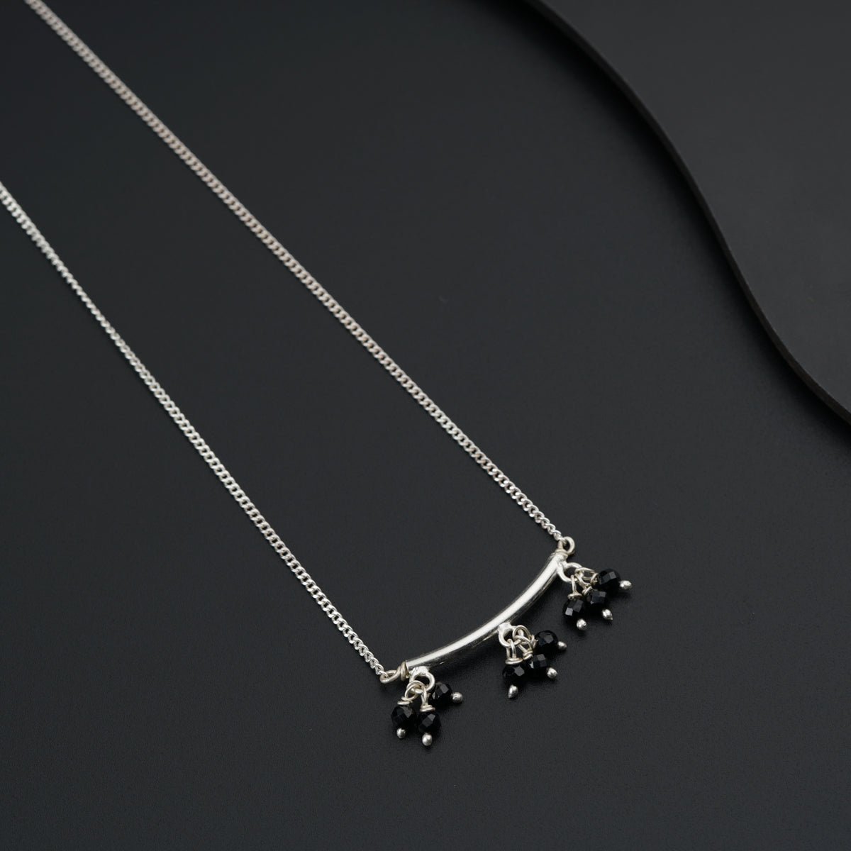 a black and silver necklace on a black surface