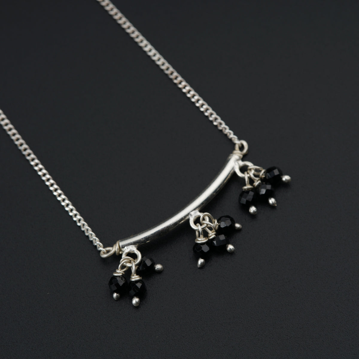 a silver necklace with black beads hanging from it