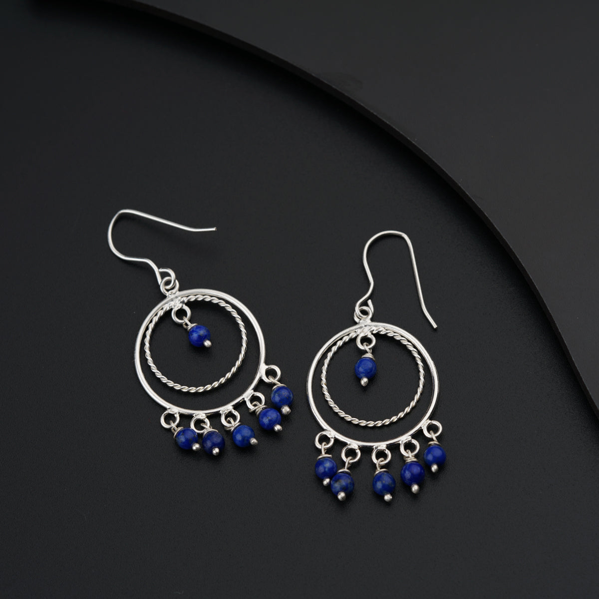 a pair of earrings with blue beads on a black surface