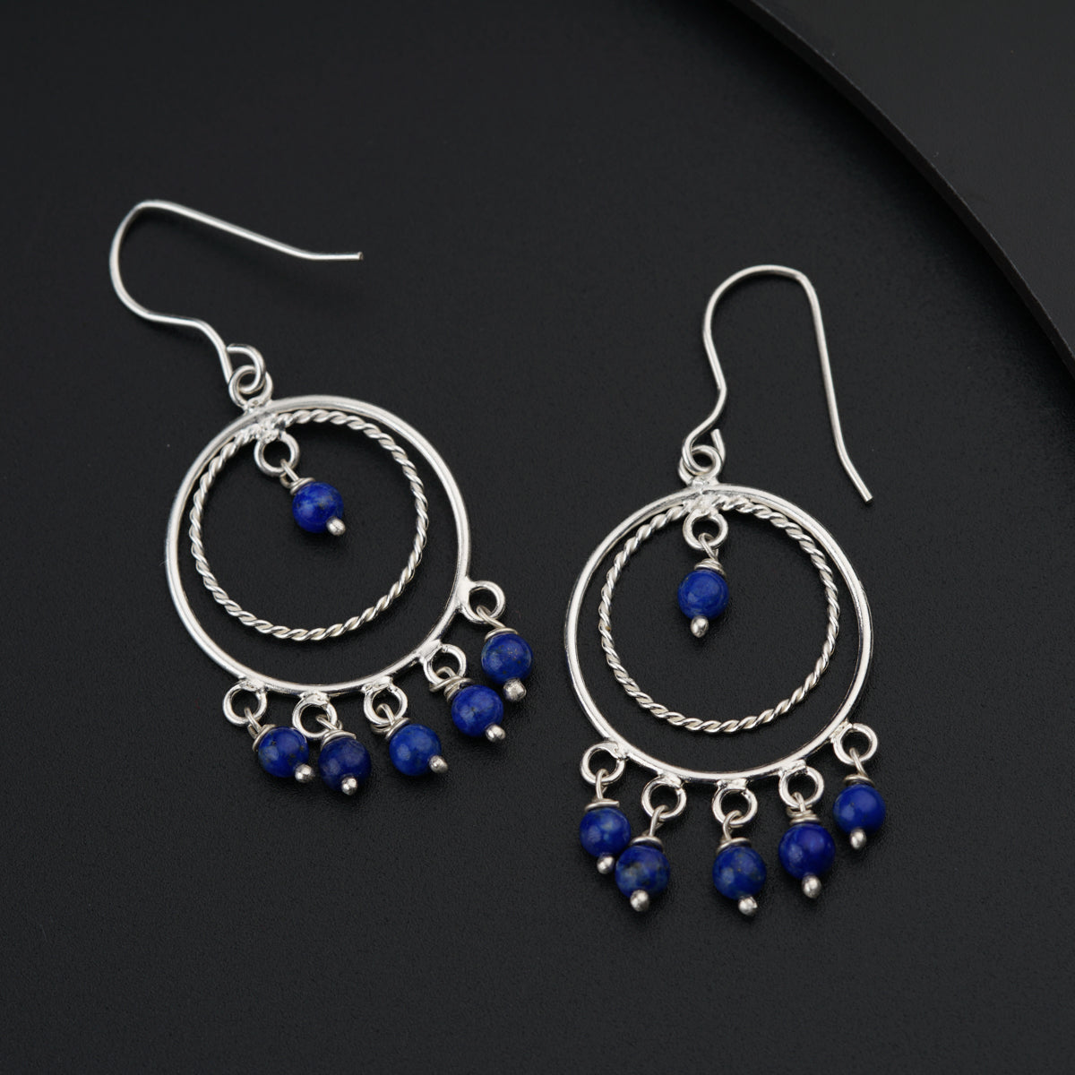 a pair of blue beads hanging from a pair of silver hoop earrings