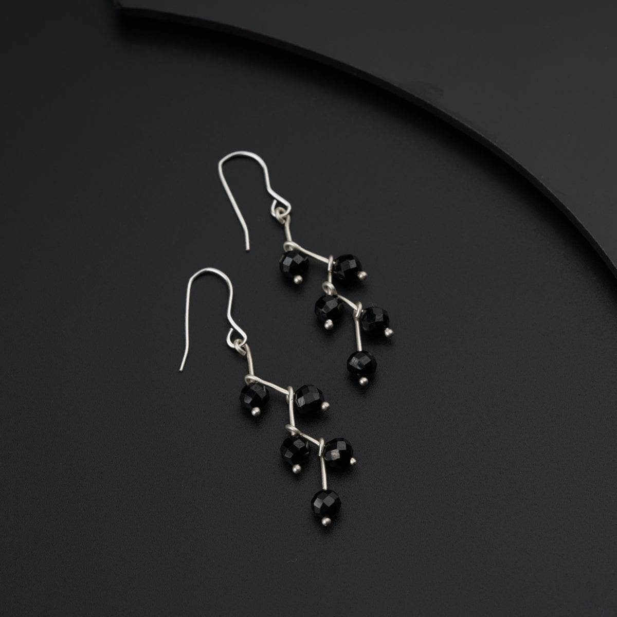 a pair of black beaded earrings sitting on top of a table