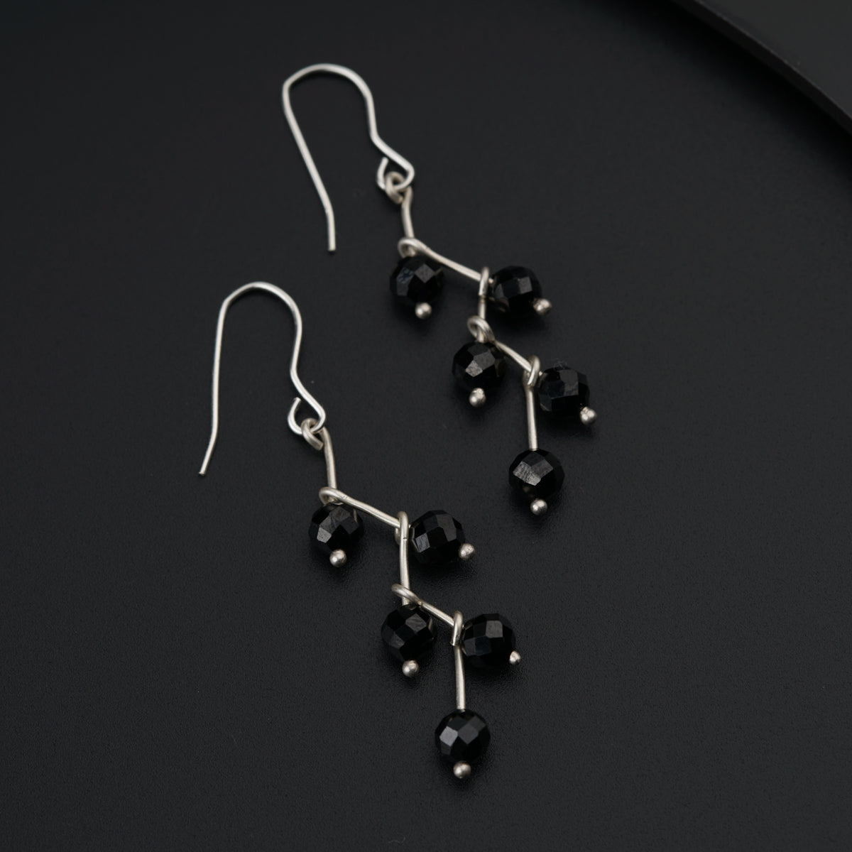 a pair of black glass beaded earrings on a black surface