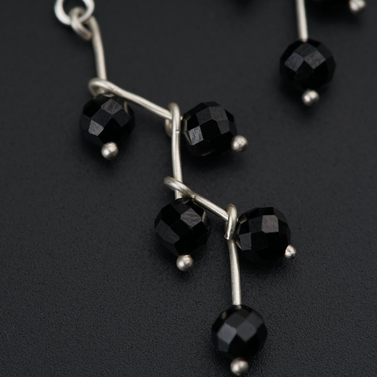 a pair of black glass beaded earrings on a black surface
