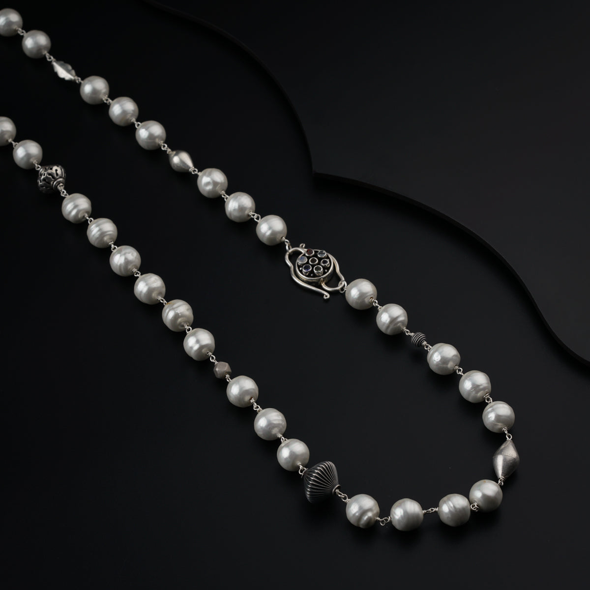 a long necklace with pearls on a black background