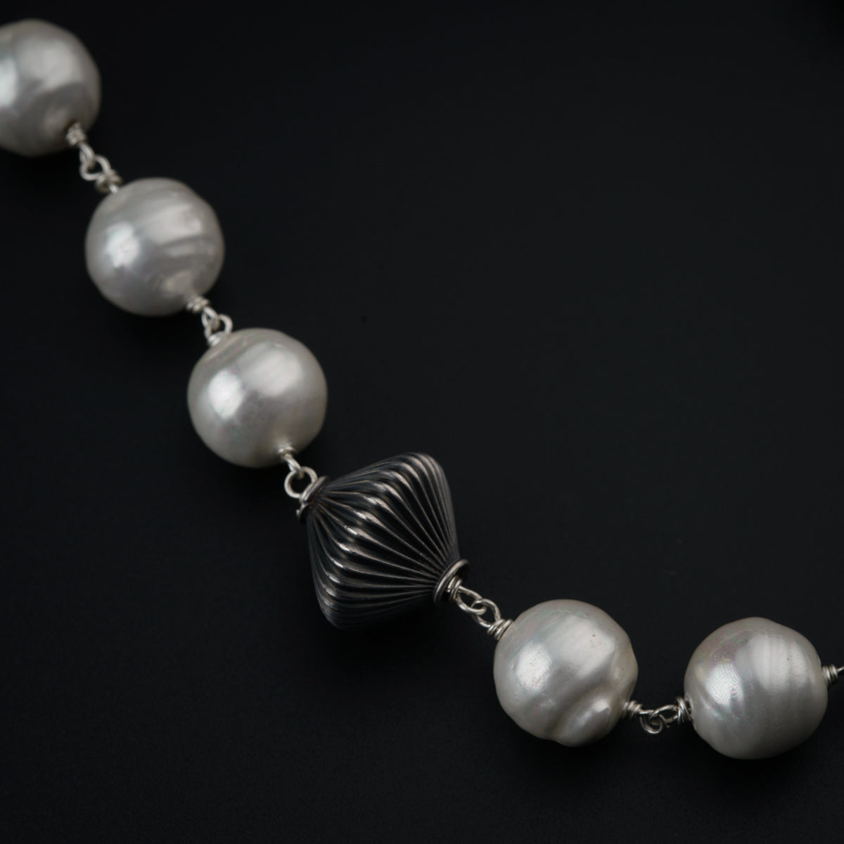 a necklace with pearls and a shell on a black background