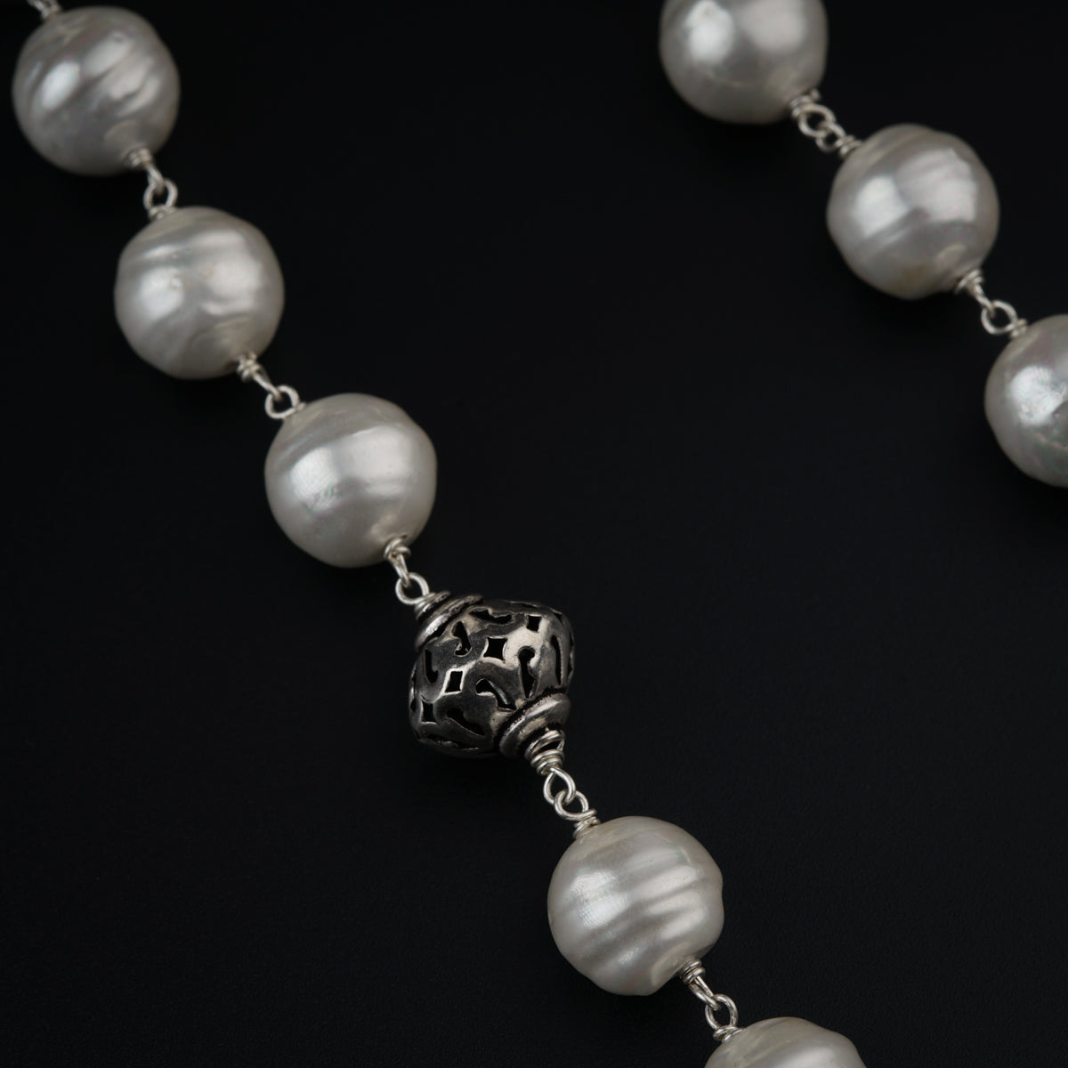a necklace with a skull and pearls on a black background