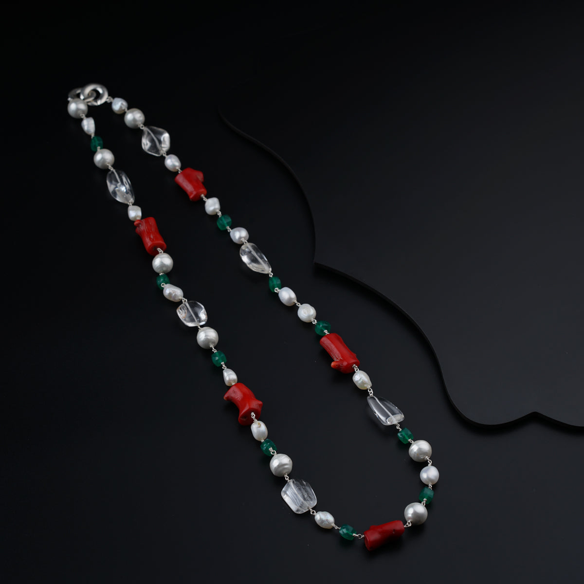 a red and green beaded necklace on a black surface