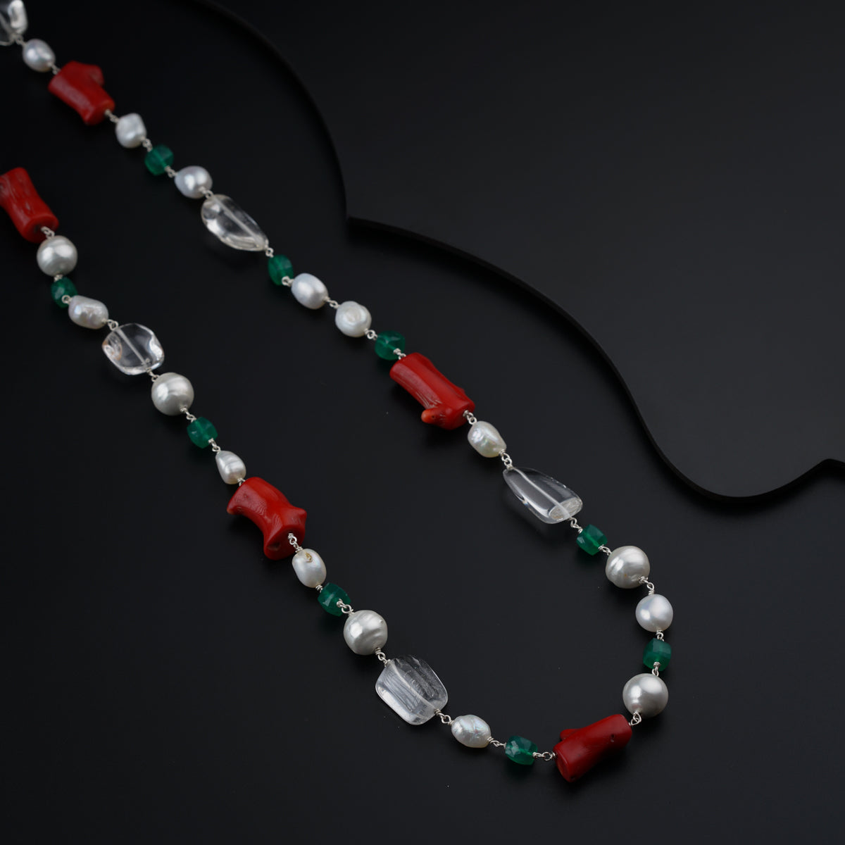 a long necklace with a red and green bead