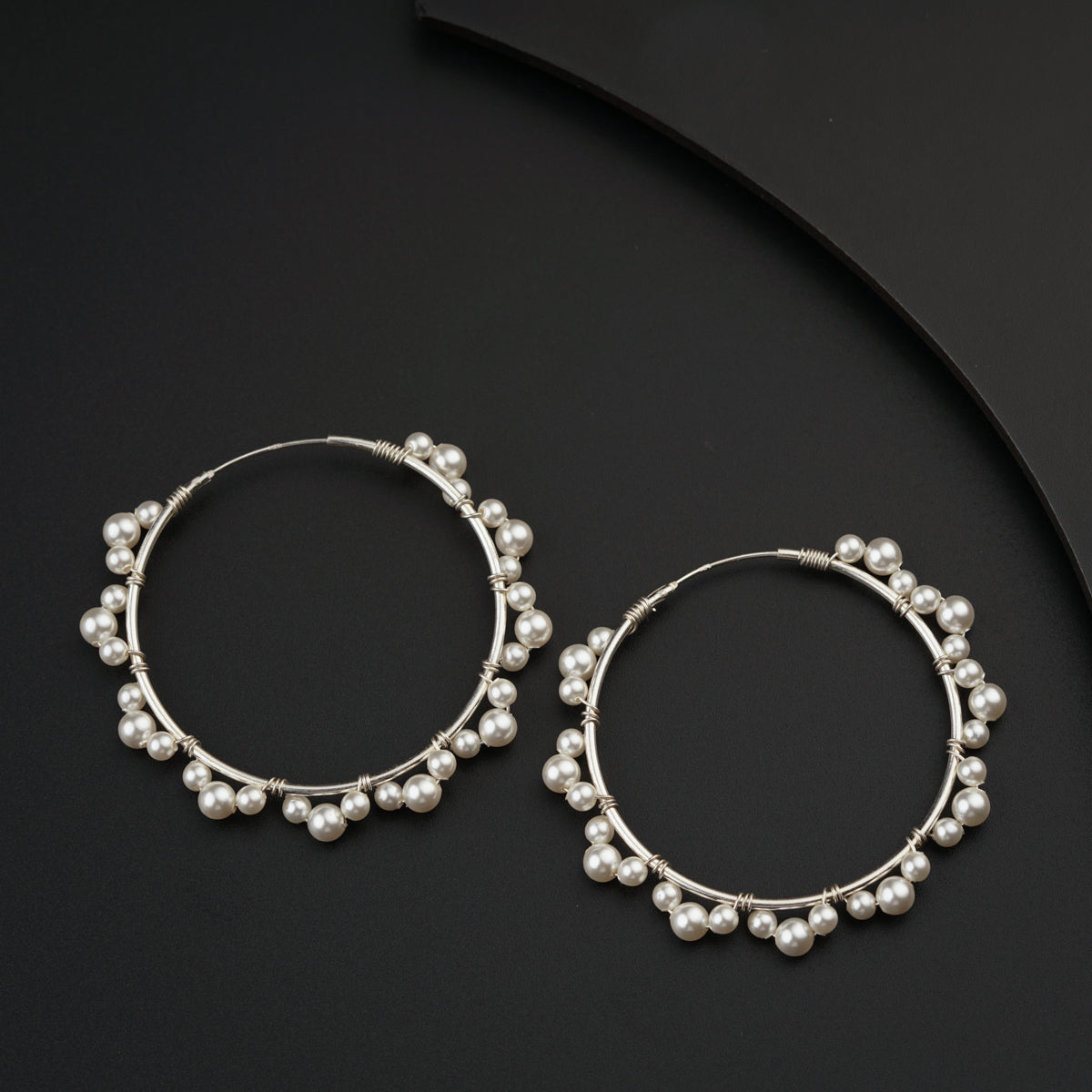 a pair of silver hoop earrings with pearls