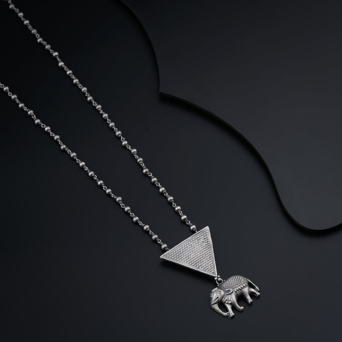 a necklace with an elephant and a triangle on it