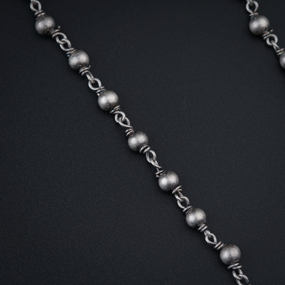 a chain of silver beads on a black background
