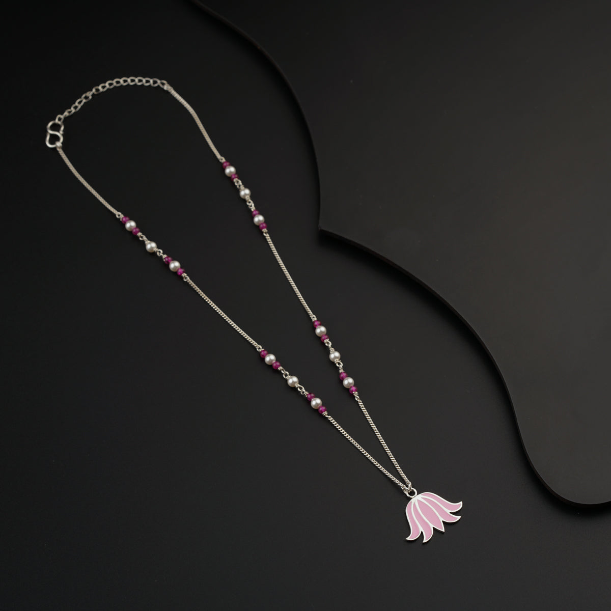 a long necklace with a pink flower on it