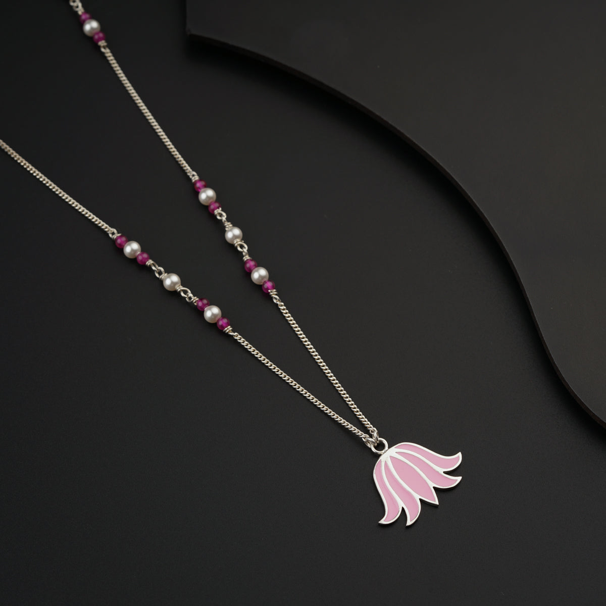 a necklace with a pink flower on it