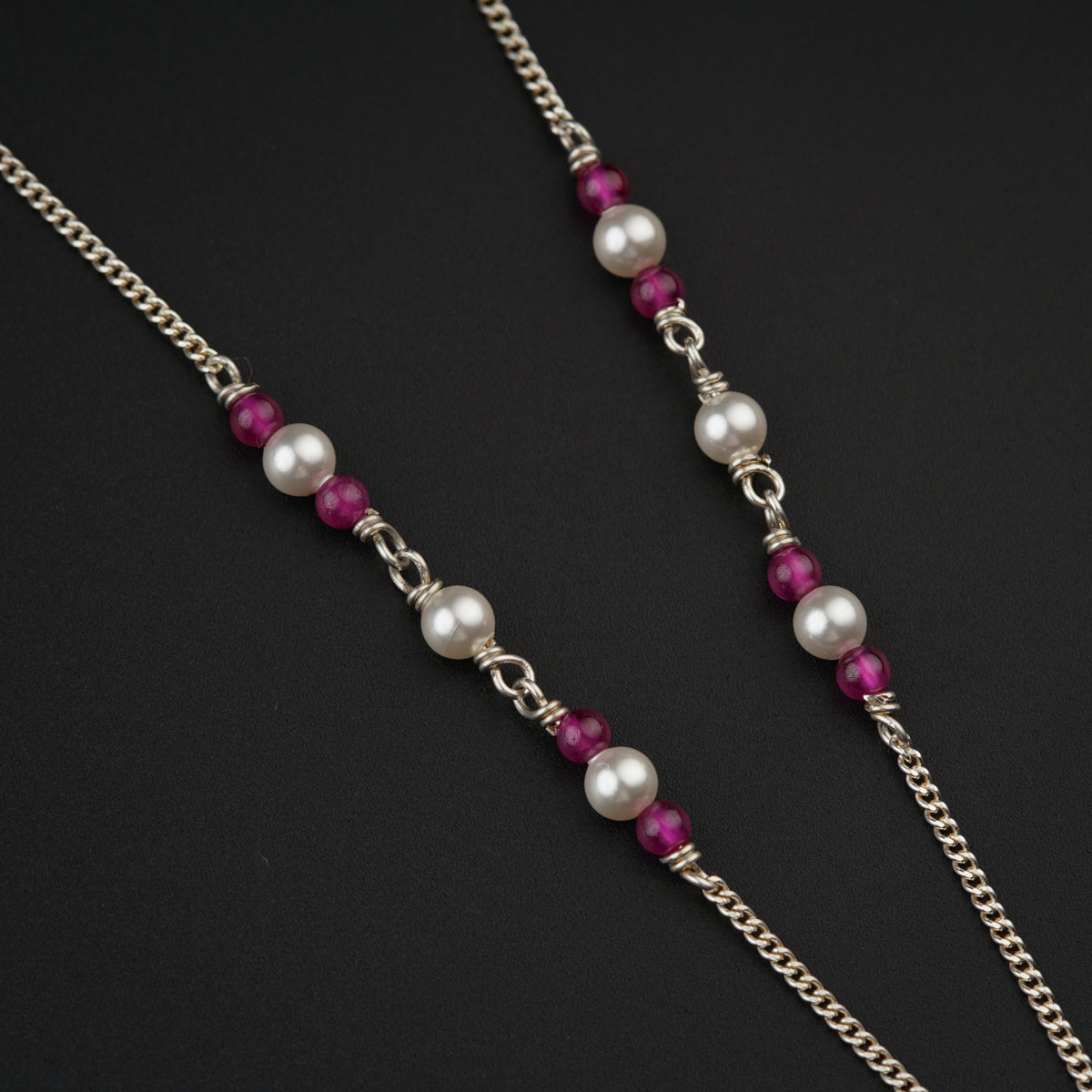 a close up of two necklaces on a black surface