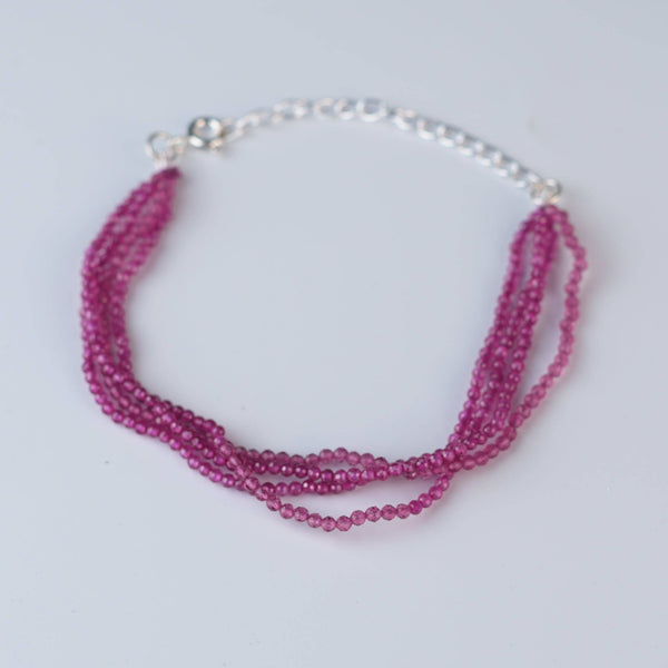 Flat-lay of a ruby silver bracelet with natural ruby gemstones and complementary handcrafted silver jewelry