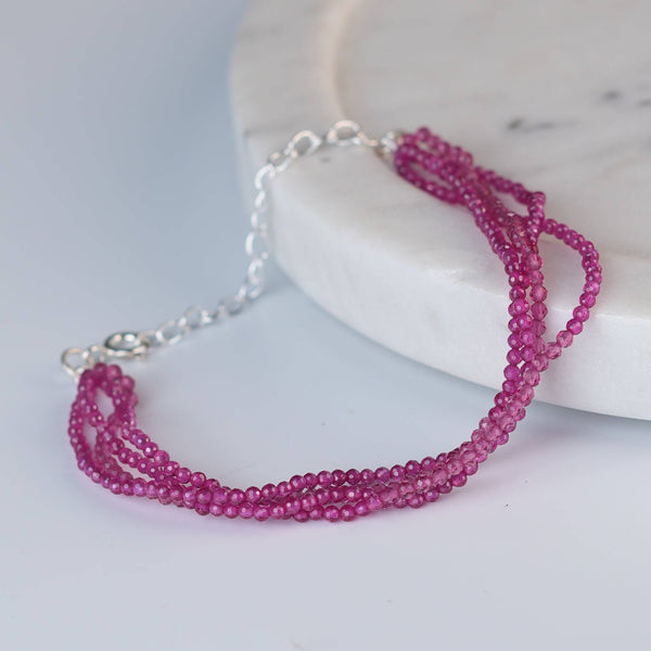 Angled view of a ruby silver bracelet in 92.5 sterling silver with elegant ruby stone detailing