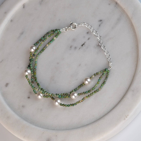 Flat-lay of Micro Firoza & Pearl Silver Bracelet with natural firoza stones, pearls, and complementary silver jewelry