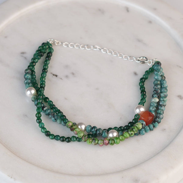 Flat-lay of a green onyx, Pearl, carnelian cube, and Green & Blue Jade Silver Bracelet with natural gemstones, pearls, and complementary silver jewelry