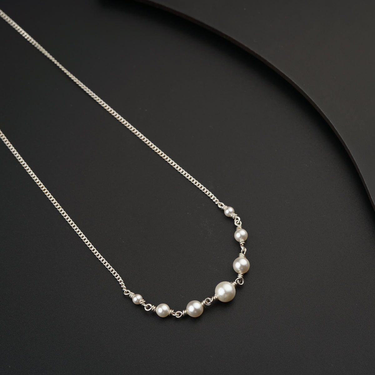 a necklace with pearls on a black surface