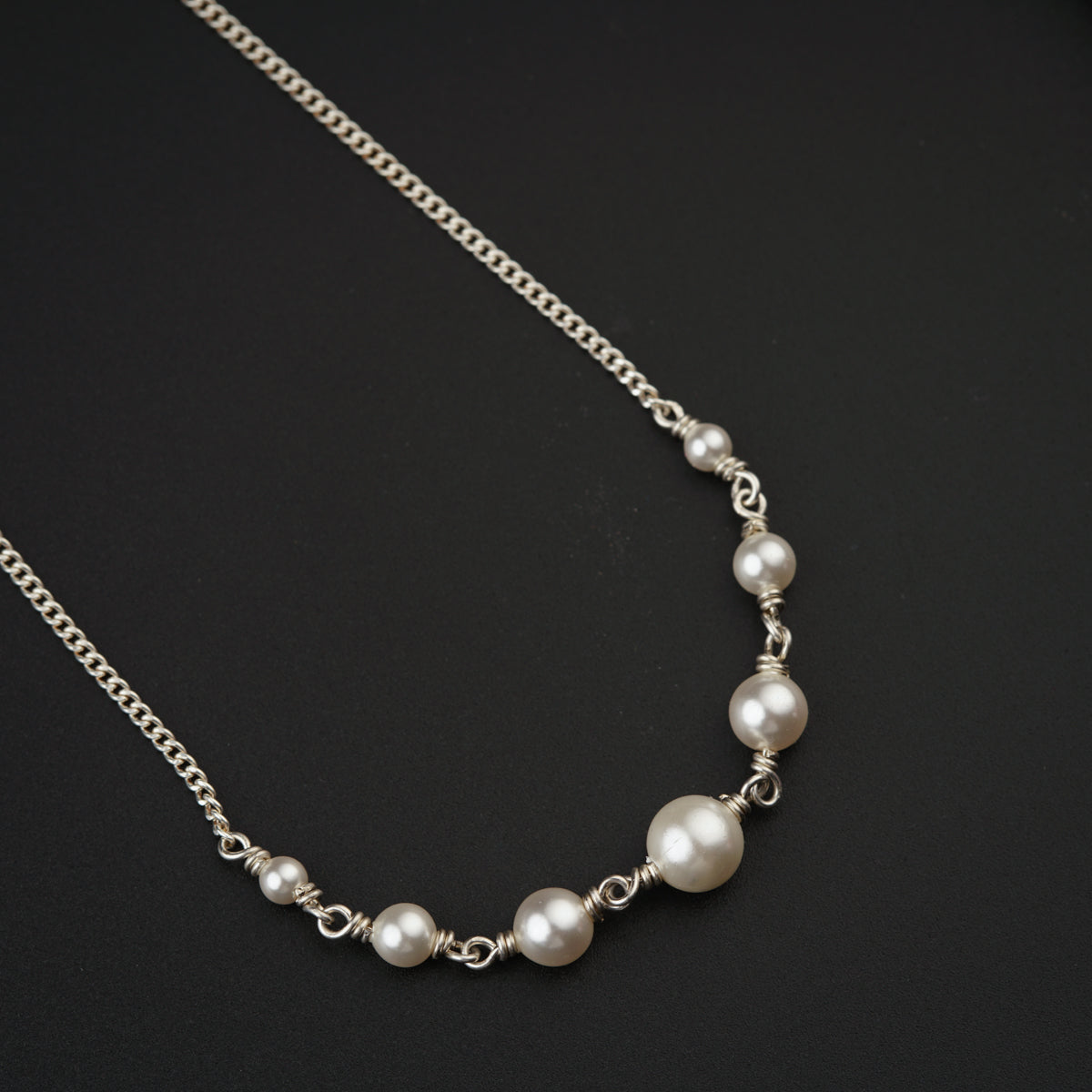 a necklace with pearls on a black surface