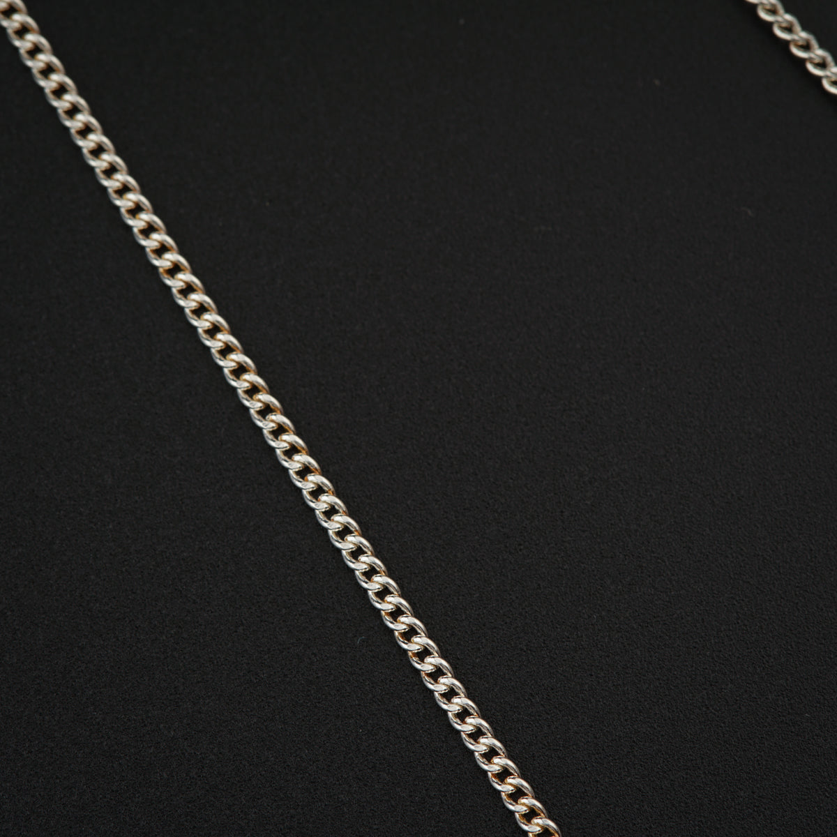 a silver chain is shown on a black surface