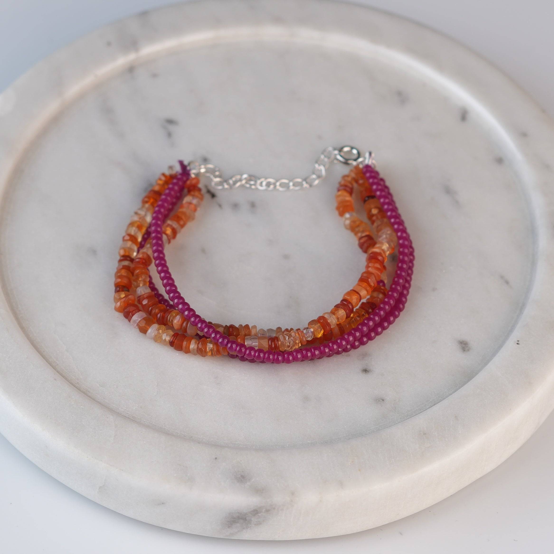 Flat-lay of Ruby & Carnelian Silver Bracelet with natural gemstones and complementary handcrafted silver jewelry