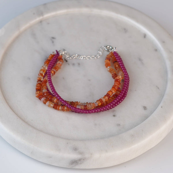 Flat-lay of Ruby & Carnelian Silver Bracelet with natural gemstones and complementary handcrafted silver jewelry