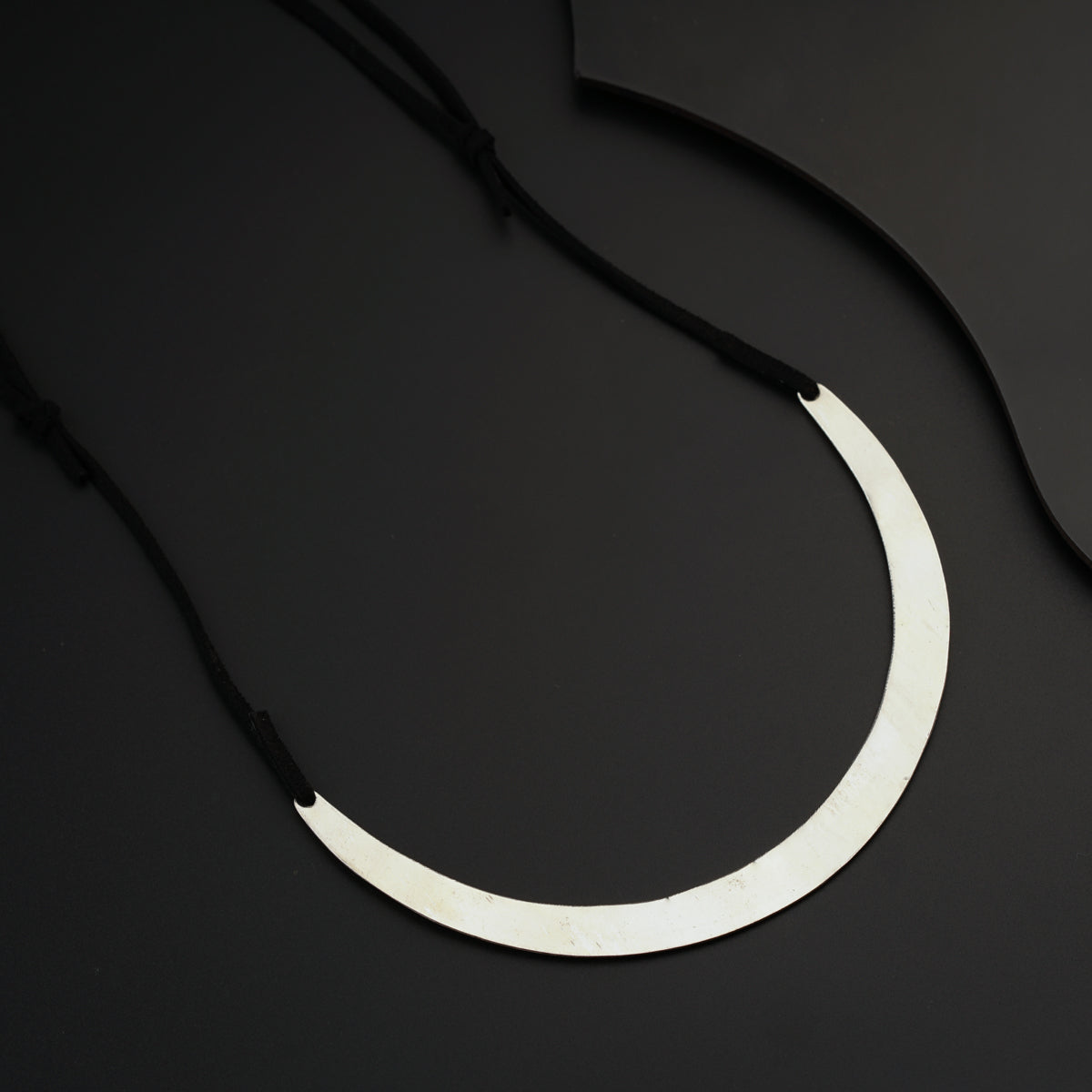 a necklace with a black cord on a black surface