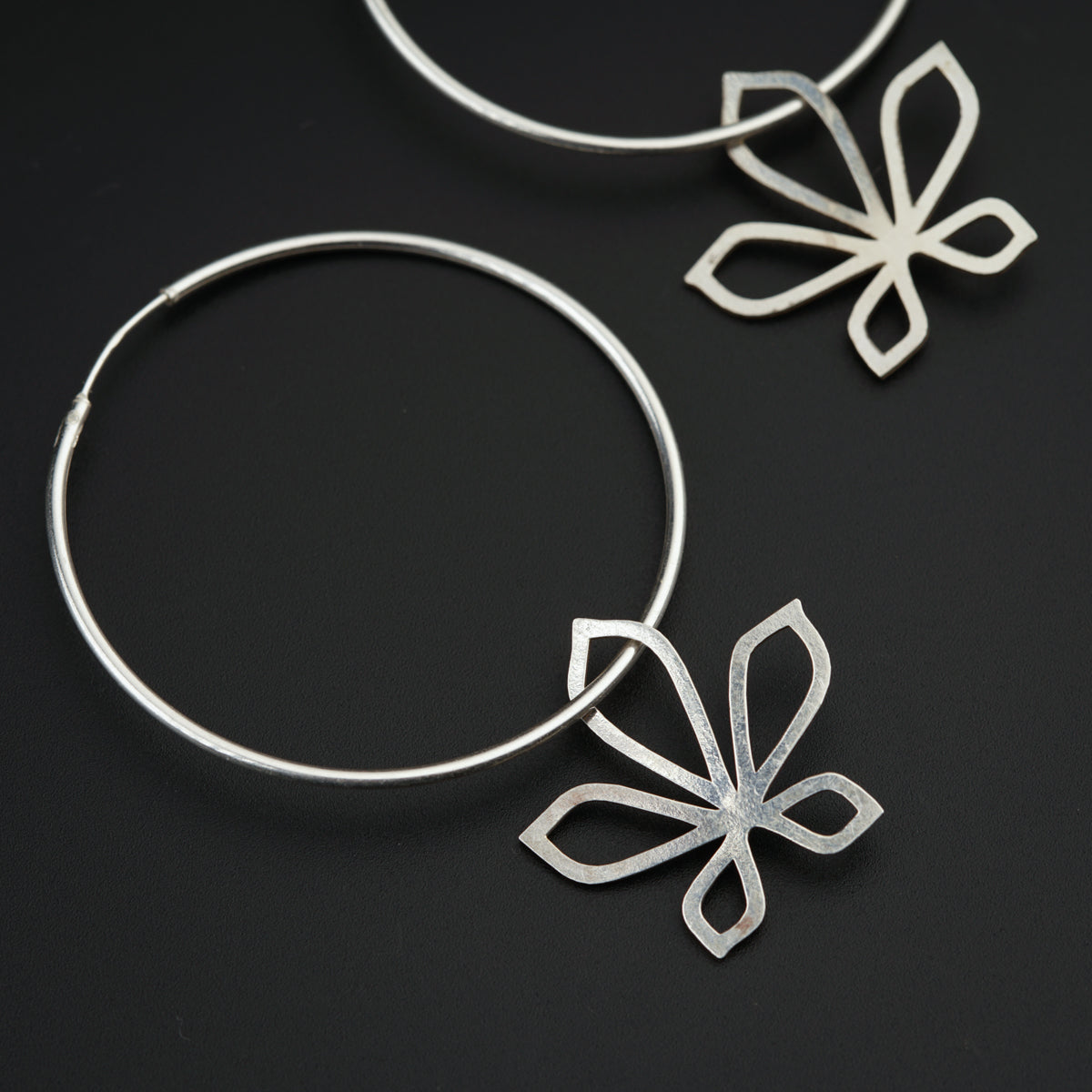 a pair of silver hoop earrings on a black surface