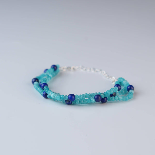 Flat-lay of a blue jade & Lapis Lazuli Silver Bracelet with natural blue jade, lapis lazuli, and complementary silver jewelry
