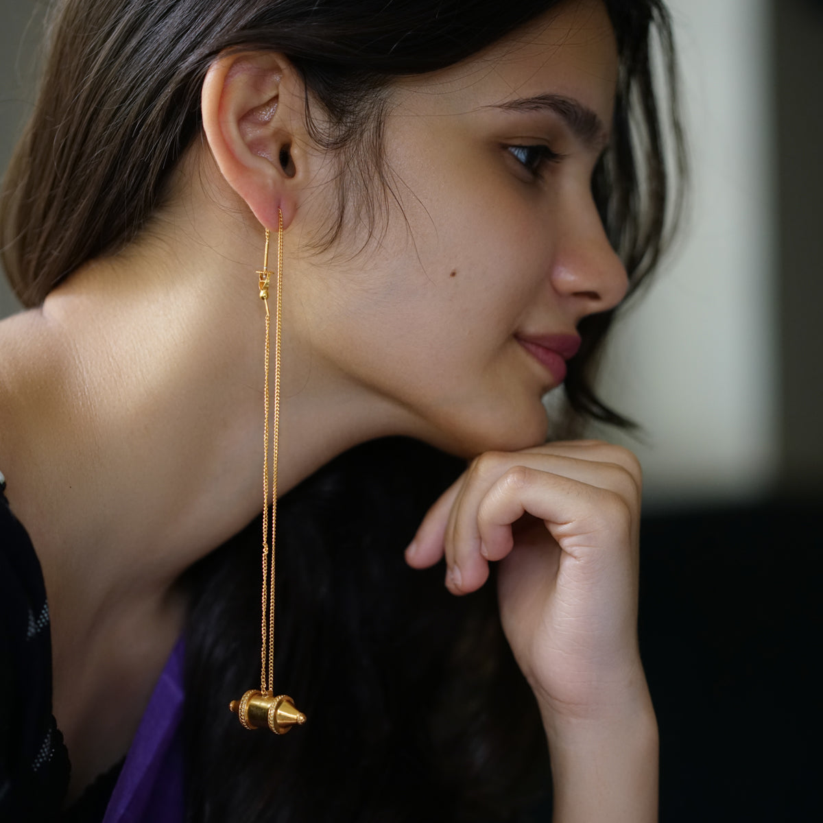 a woman wearing a pair of gold earrings